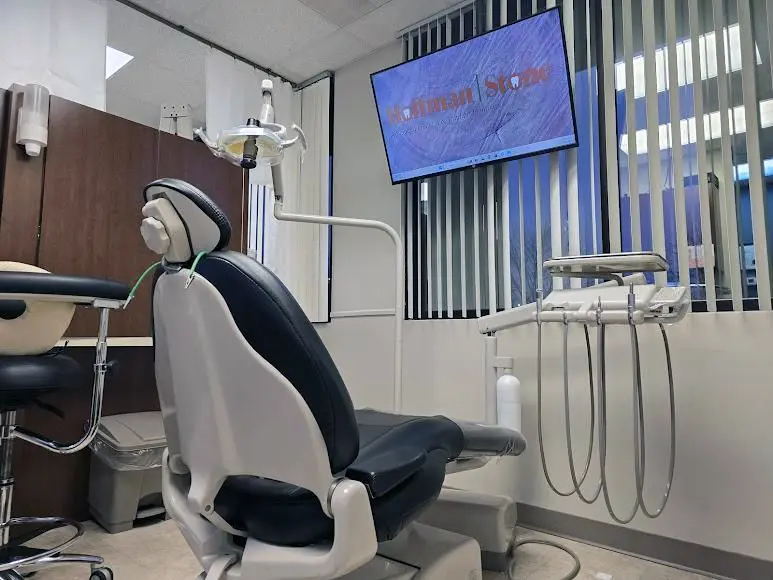 Dental Exam Room with black and white dental chair, instruments, and a monitor displaying "Hoffman Stone".