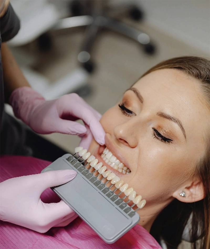 woman in dentist chair while dentist holds up a chart of teeth to match for cosmetic dentistry procedure