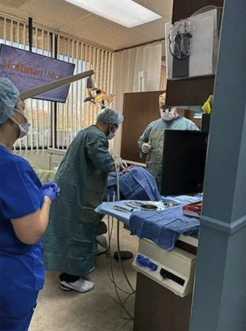 dentists and nurses in scrubs with patient in chair leaning back with face covered as the dentist performs emergency dental care