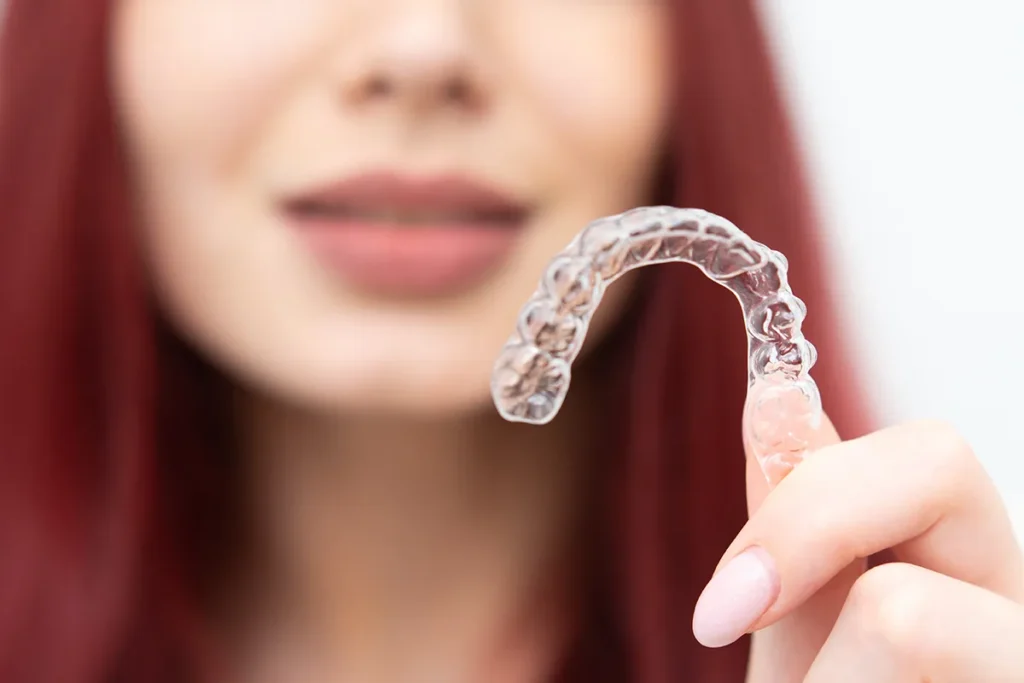 woman-holding-clear-orthodontic-aligner-for-teeth